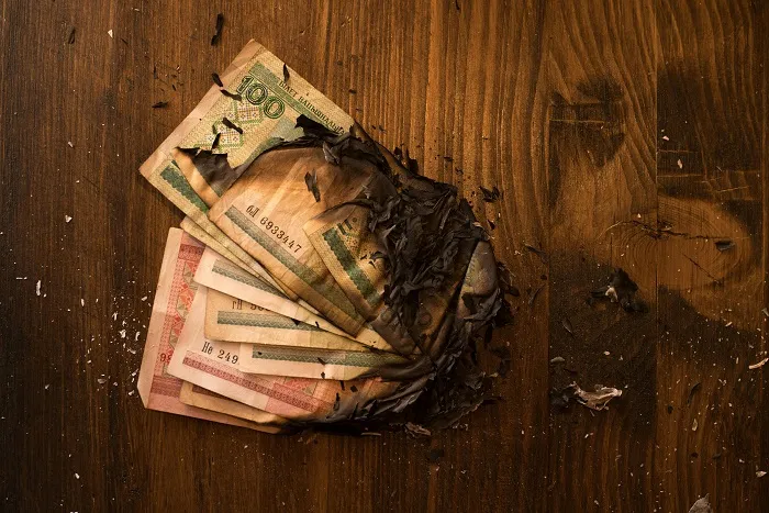 Illustration of a partially burned roll of banknotes. Symbol of financial losses.